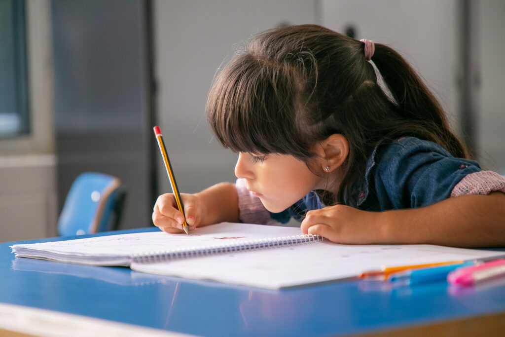 focused black haired latin girl sitting at school desk