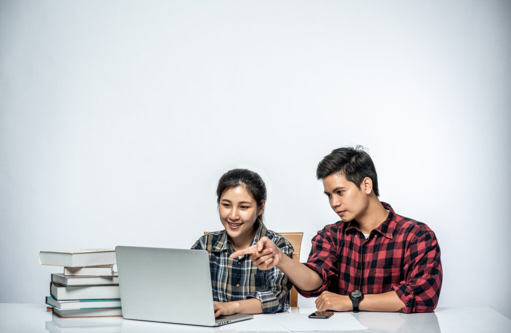 men teach women how to work with laptops at work.